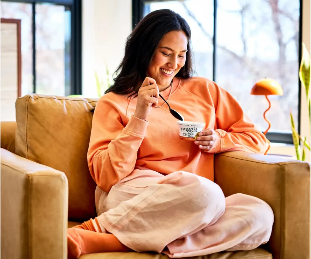 woman eating a siggi's fruit & fiber in a chair